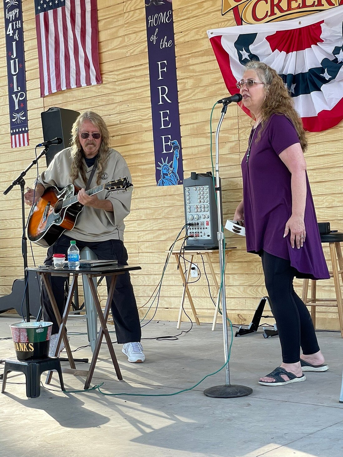 Two people singing and playing guitar on a stage